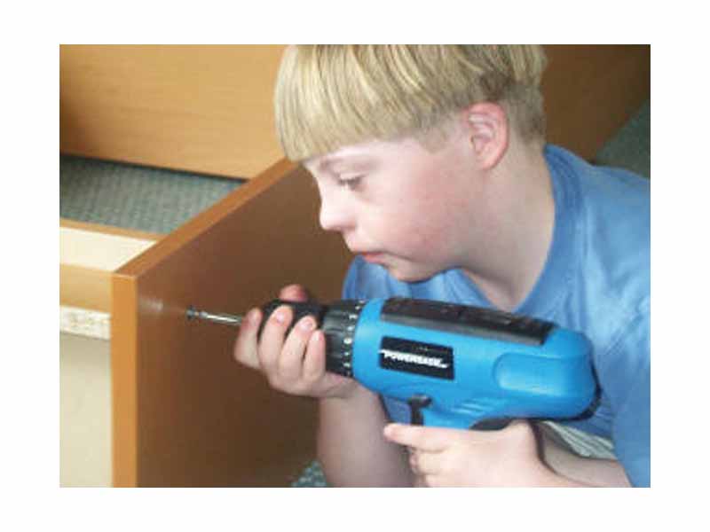 Boy with Down syndrome assembling a bookcase